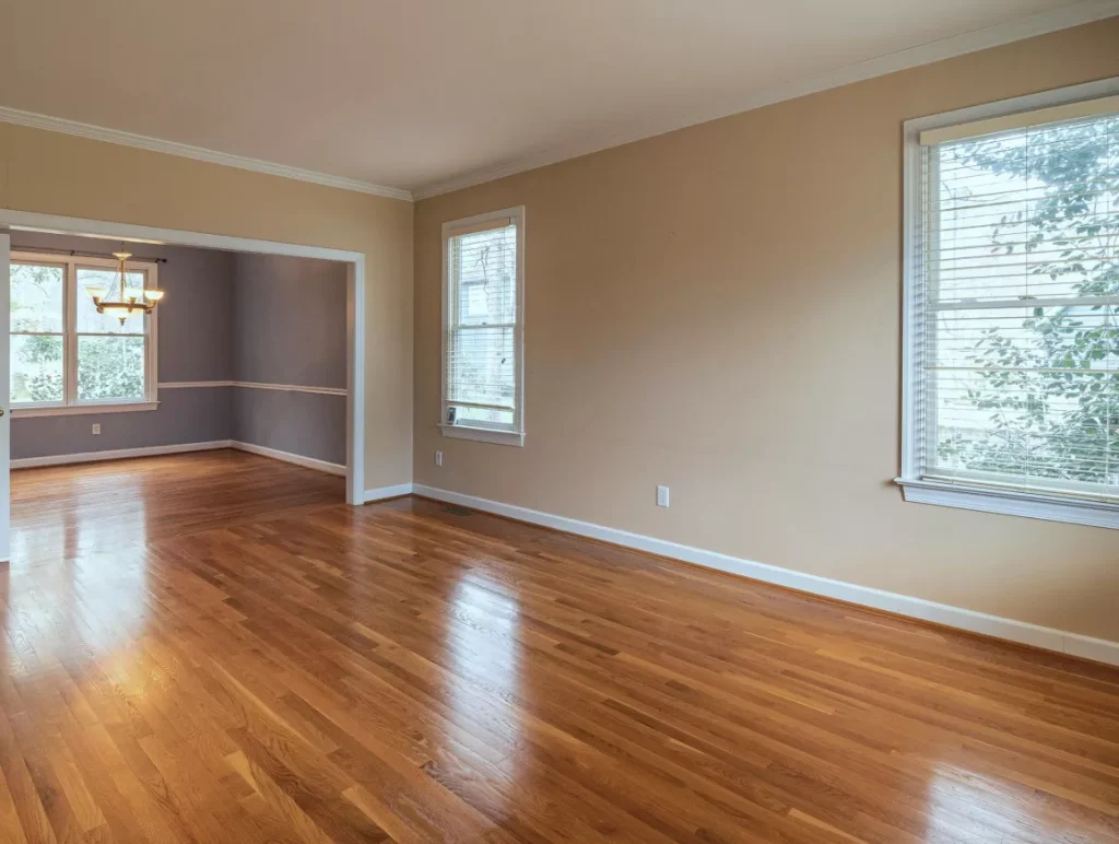 Empty living room featuring hardwood floors and large windows allowing natural light to fill the space.