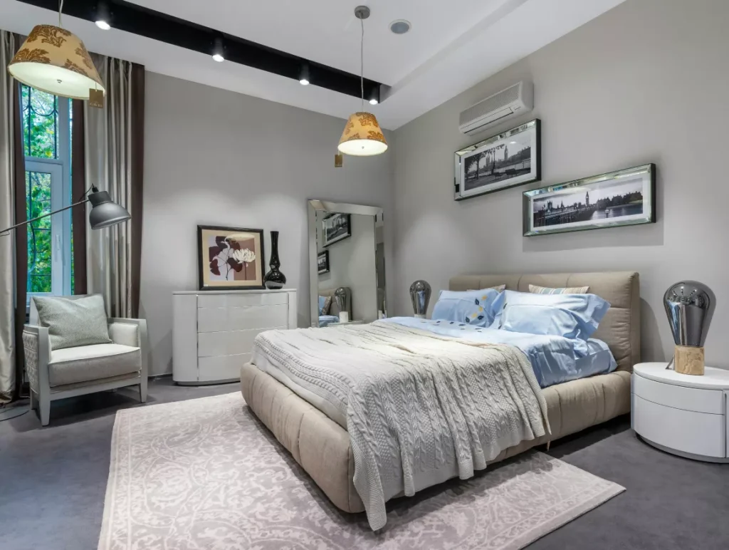 A spacious bedroom featuring a large bed and an expansive mirror reflecting the room's decor.