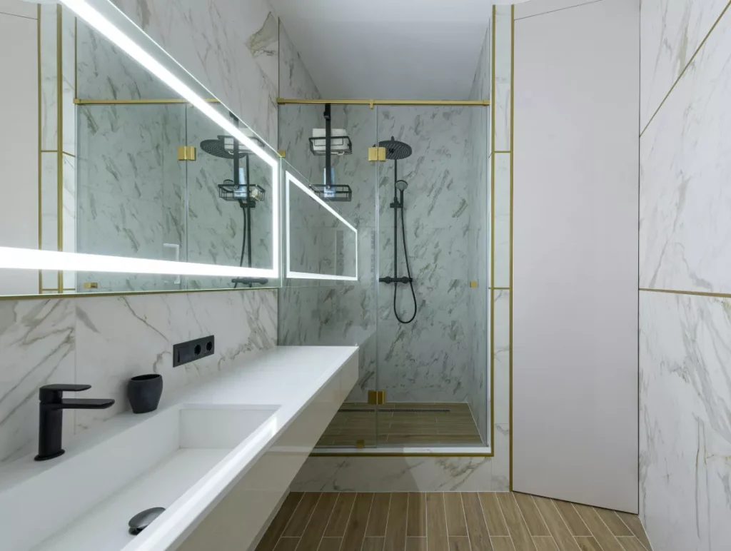 A luxurious bathroom featuring a polished marble floor and elegant gold trim accents.
