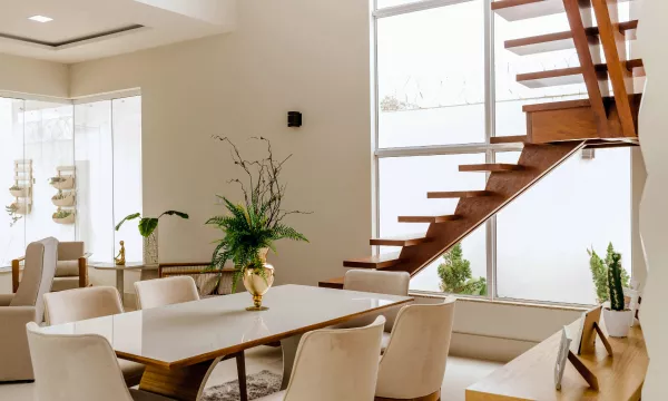 A contemporary dining room featuring a stylish table and chairs, with a staircase visible in the background.